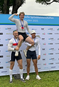 Drei Ruderer feiern ihre Siege, Bronze und Silber heben Gold in die Höhe.
